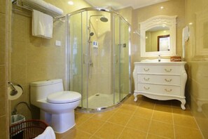A bathroom with a glass-enclosed shower, a white toilet, a vanity with drawers, and a mirror above the sink. - Xiangxing Hotel (Zhongshan)