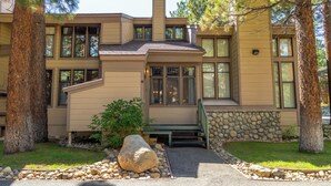 A modern two-story house with a stone foundation, large windows, and a stone retaining wall. - Beautiful St Moritz Family Home 560 (Mammoth Lakes)