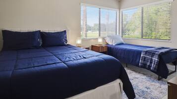 Une chambre avec deux lits, une table de chevet et une fenêtre avec des stores.