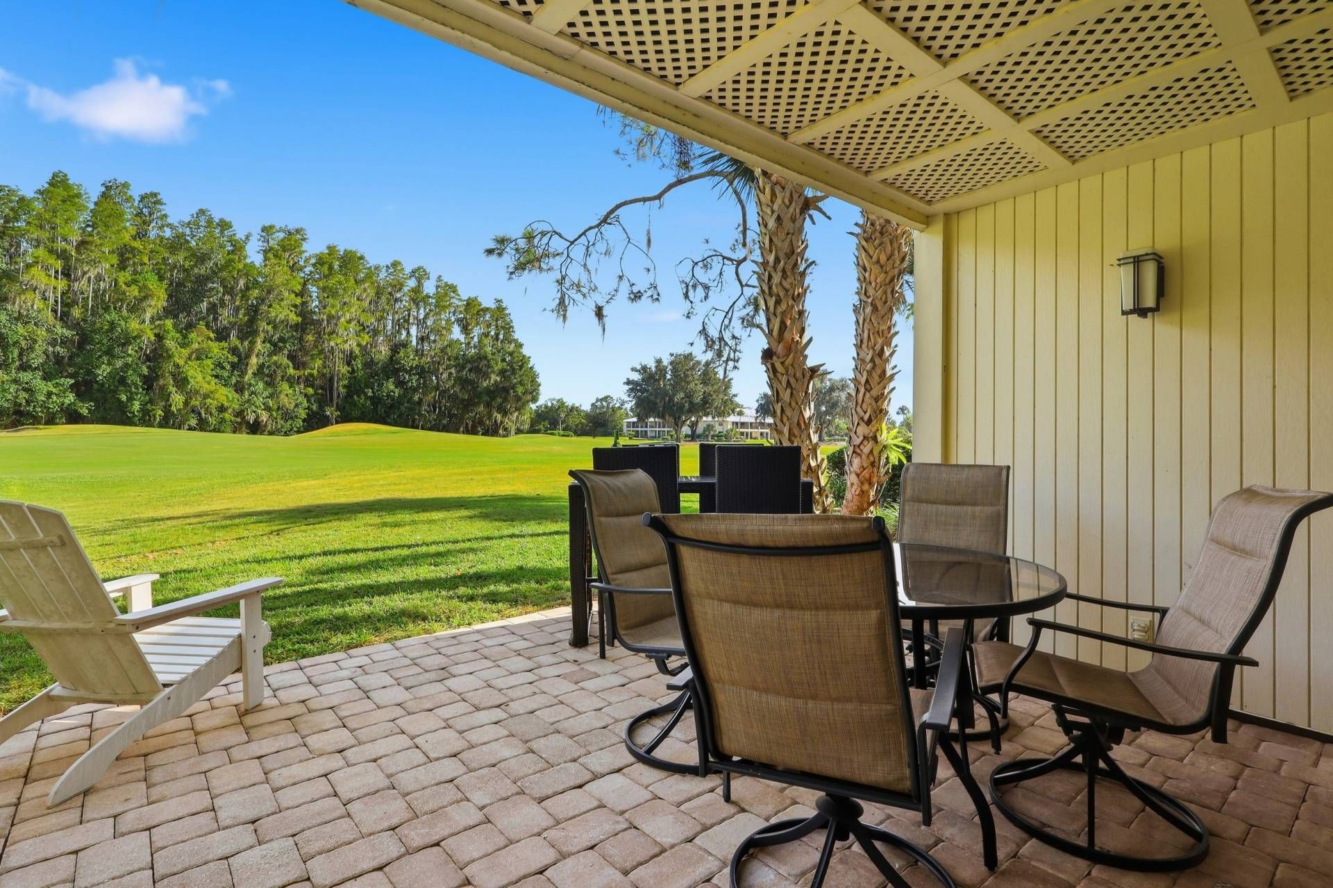 Une terrasse avec mobilier d’extérieur, une vue sur un terrain de golf et un bâtiment dont le revêtement extérieur est constitué de panneaux verticaux.