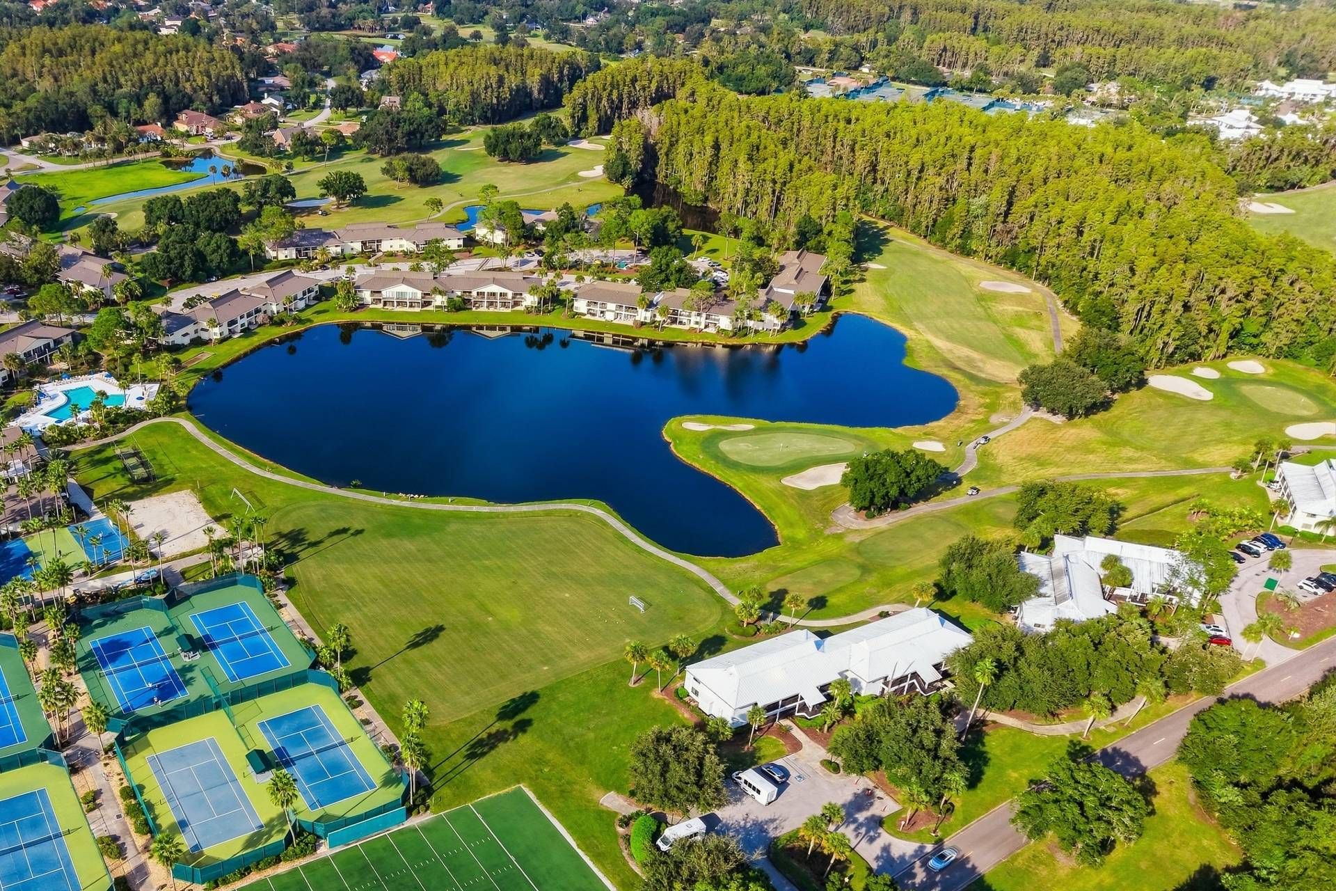 Un parcours de golf avec un grand lac, des courts de tennis et des immeubles résidentiels.