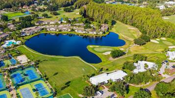 Un parcours de golf avec un grand lac, des courts de tennis et des immeubles résidentiels.