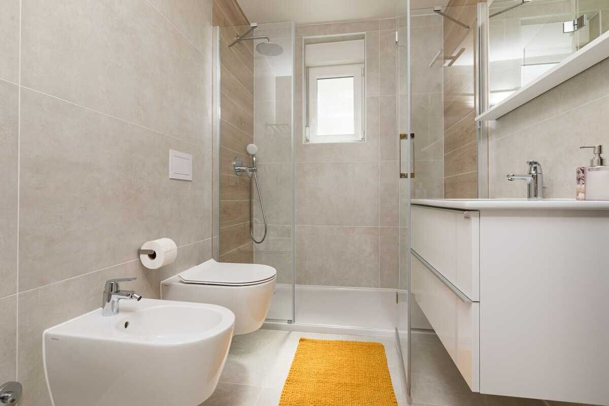 Et moderne badeværelse med brusebad, toilet, bidet og håndvask.