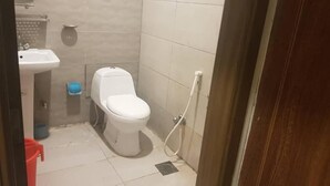 A small bathroom with a toilet, sink, and shower.