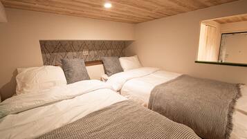 A bedroom with two beds, a wooden ceiling, and a headboard with a leaf pattern.