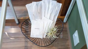 A metal wire basket containing several white bags labeled "razor" and "cotton set" on a wooden floor.