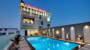 Um hotel com piscina, design moderno e uma placa com a inscrição 'Clarion Hotel'.