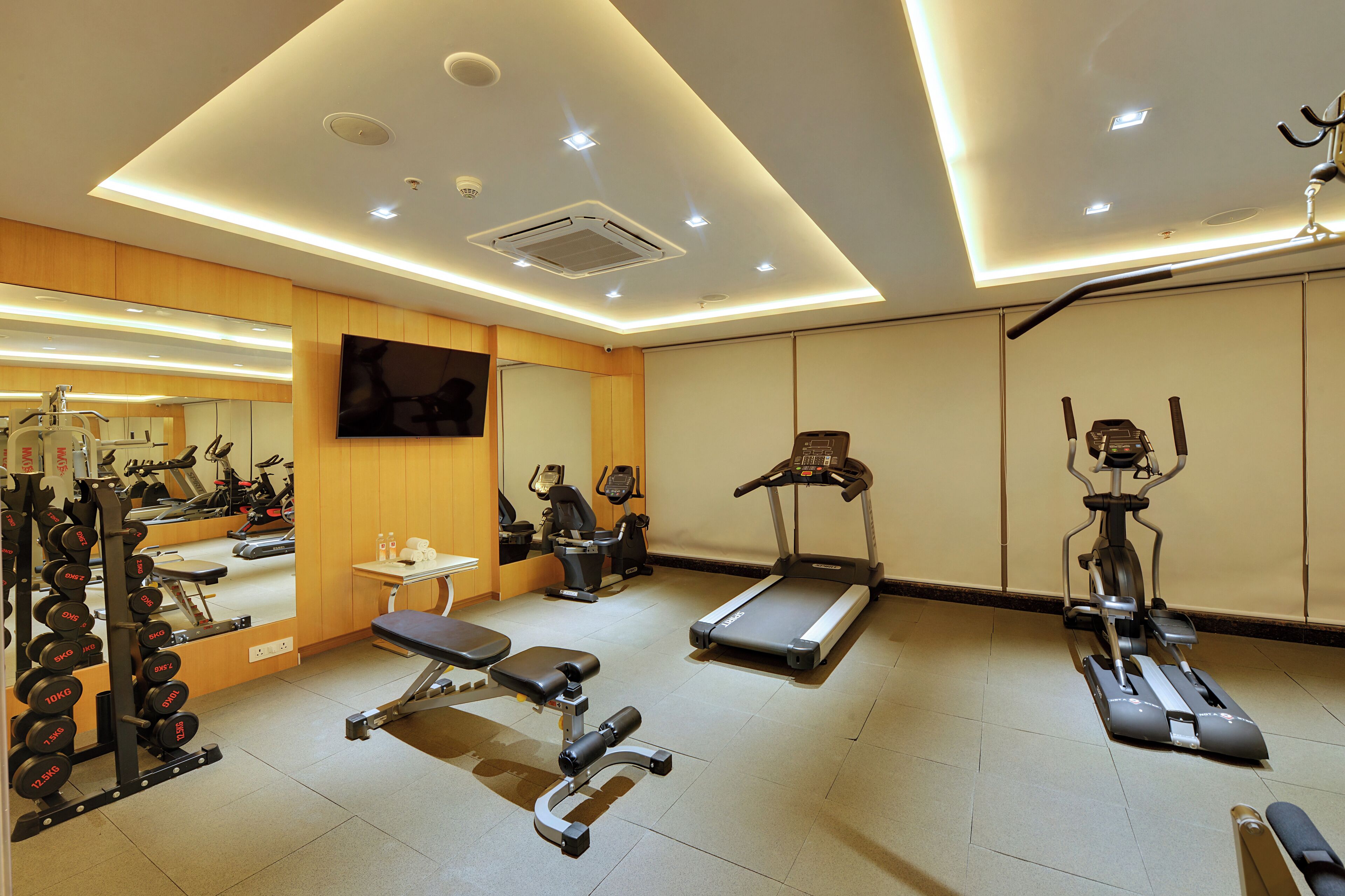 A modern gym with various exercise equipment, including treadmills, a stationary bike, and weightlifting stations.
