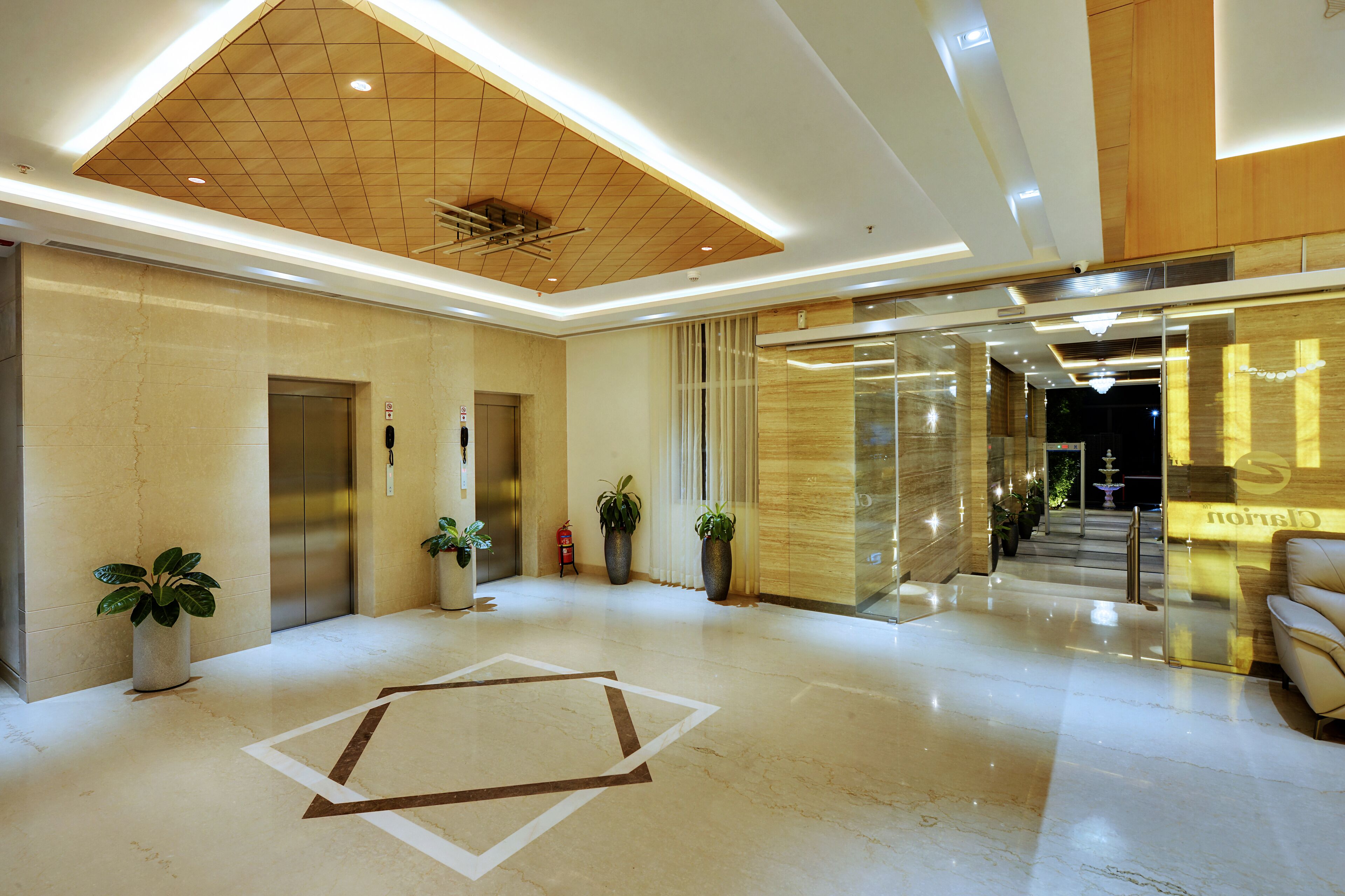 Un hall d’hôtel moderne avec un sol en marbre, un comptoir d’accueil, un escalier et un plafond doté d’un éclairage encastré.