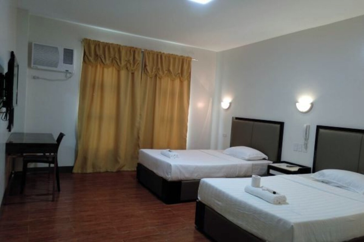 Une chambre d’hôtel avec deux lits, un bureau et une chaise.