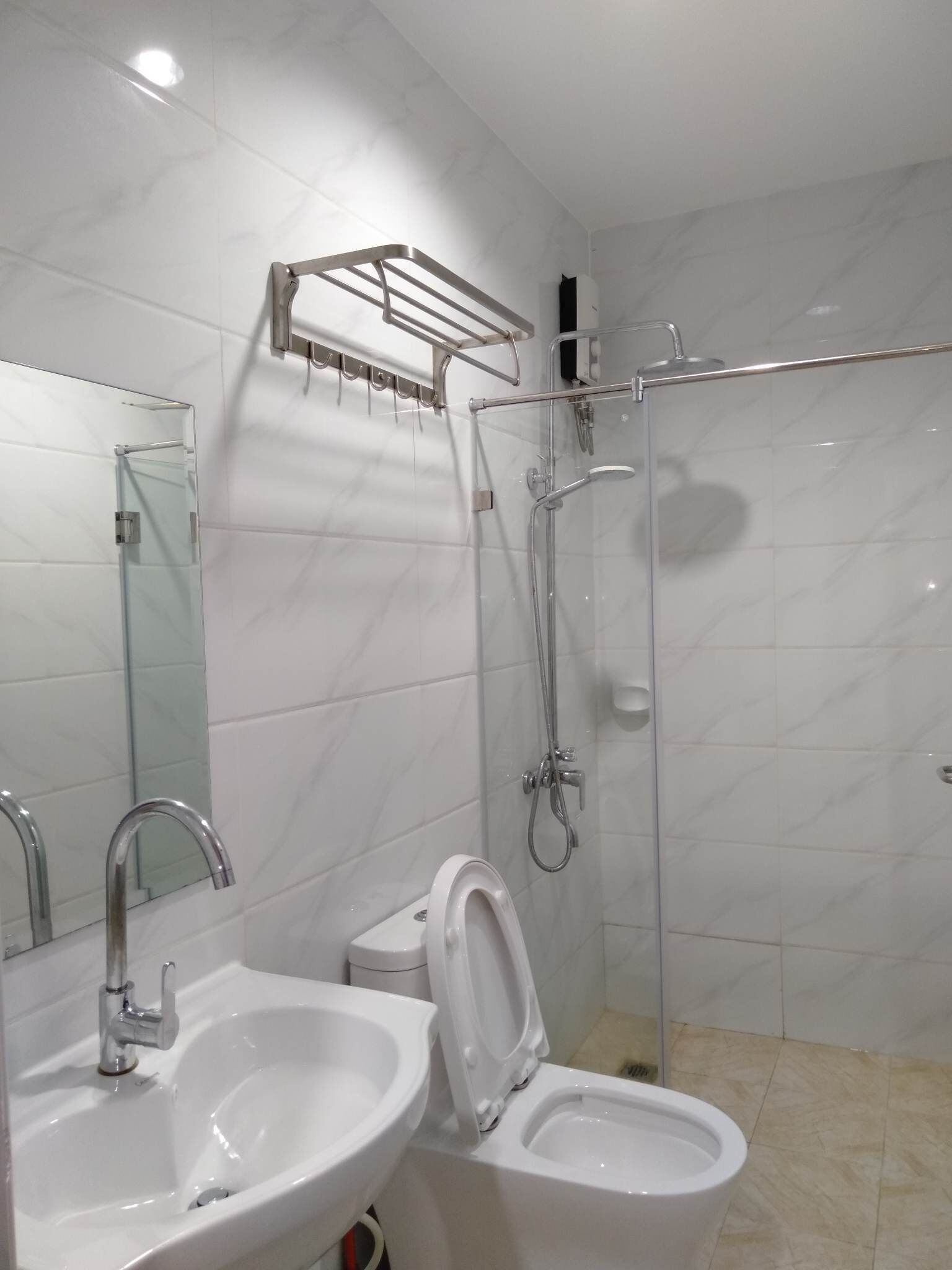 Une salle de bain moderne dotée d’une douche à parois de verre, d’un lavabo et de toilettes.