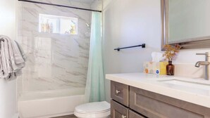 A bathroom with a bathtub, toilet, and vanity with a mirror. - Renton lovely 2-bedroom apartment free parking (Renton)