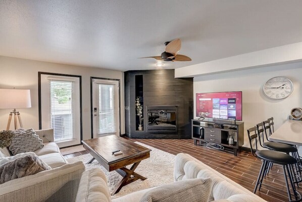 A modern living room with a fireplace, a TV, and a dining area.