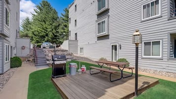 Un edificio residencial con terraza, parilla y mesa de picnic.