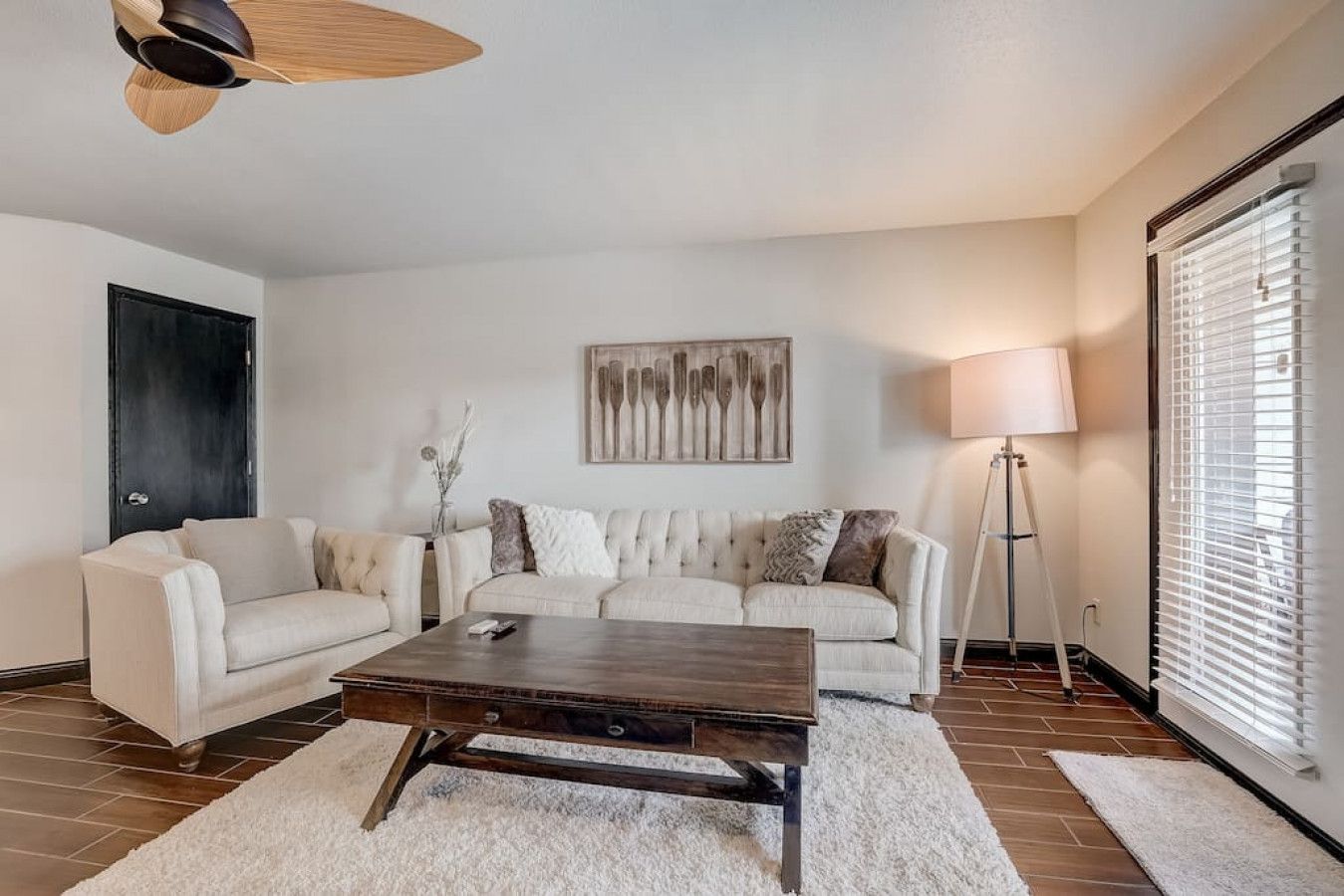 Una sala de estar con un sofá color beige, una mesa de centro de madera y una lámpara de pie.