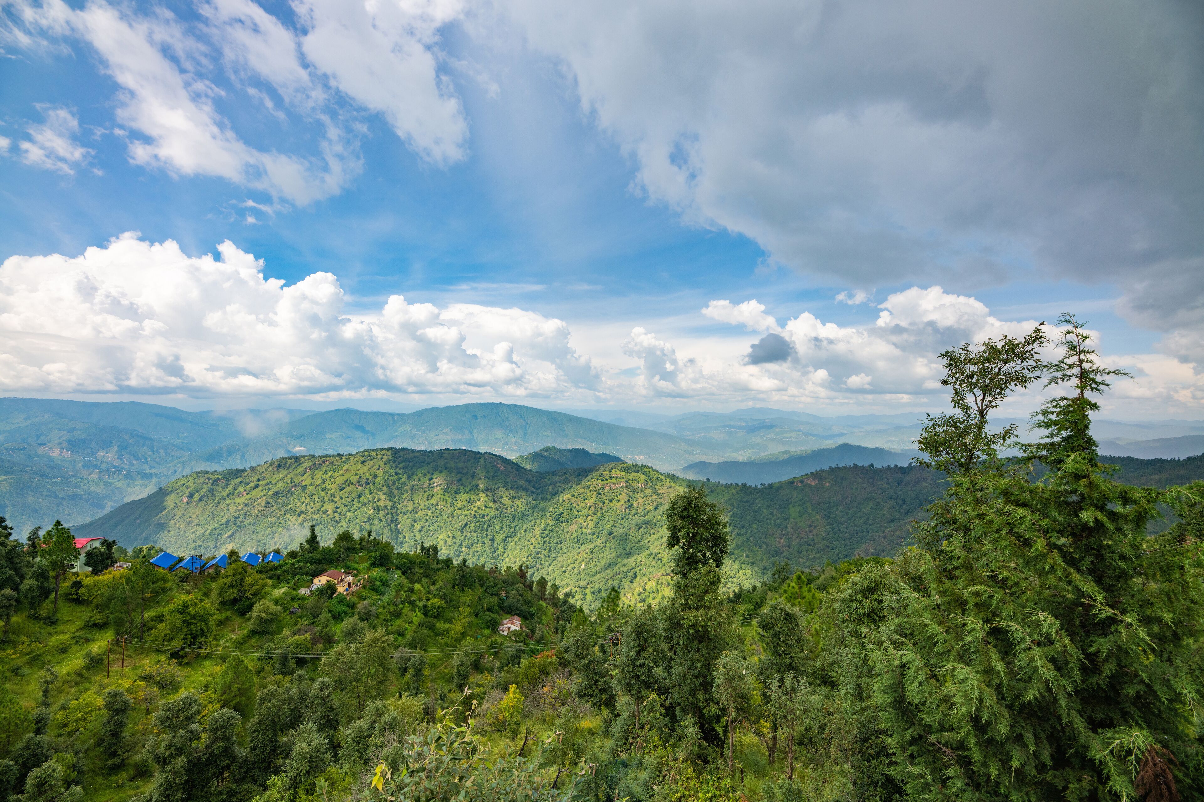 Un paysage montagneux, caractérisé par une végétation luxuriante et quelques bâtiments dispersés.