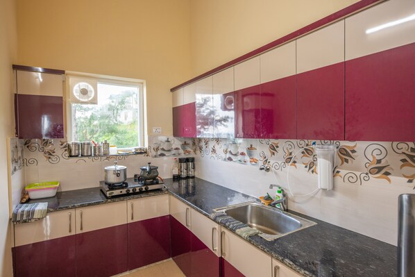 A kitchen with a gas stove, sink, and various kitchen utensils. - Hotel Him Darshan Cottage By F9 Hotels (Champawat)