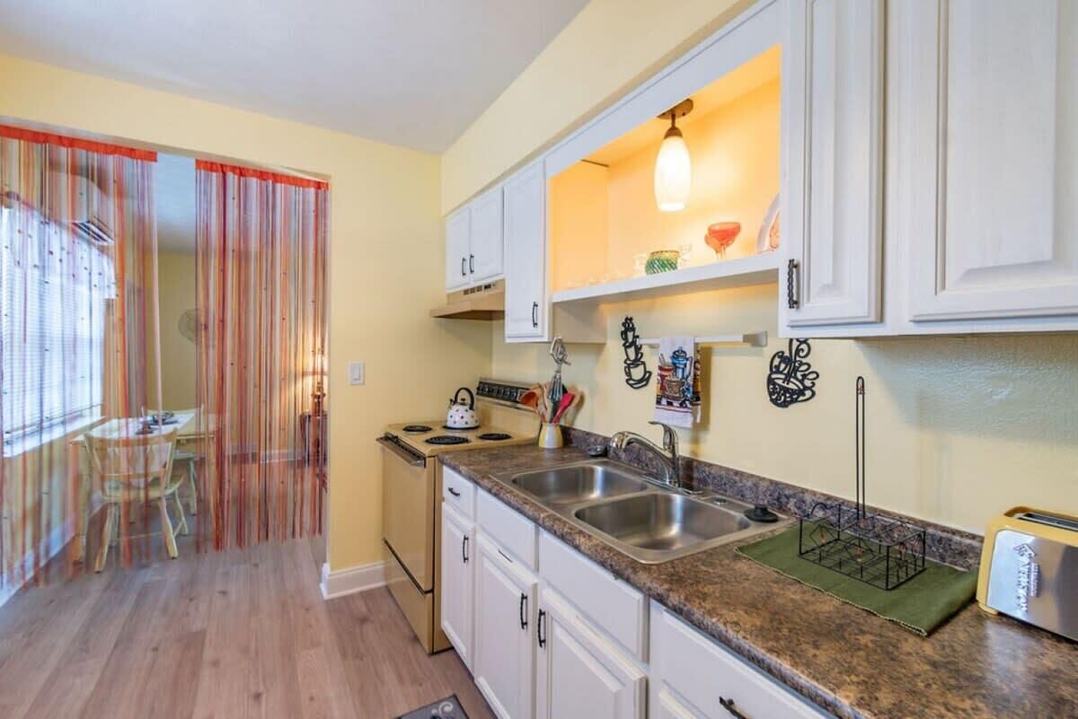 A kitchen with white cabinets, a granite countertop, a stove, and a sink.
