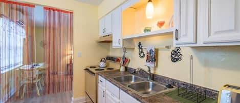 A kitchen with white cabinets, a granite countertop, a stove, and a sink.