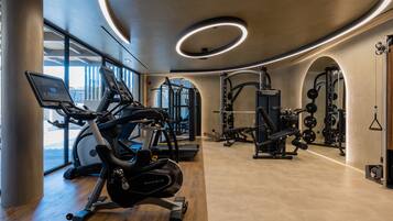 A modern gym with cardio machines, weightlifting equipment, and a large window providing natural light.