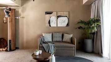 A modern living room with a sofa, a coffee table, and a large potted plant.