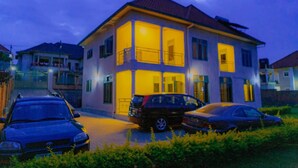 A two-story house with a balcony and a driveway with parked cars. - Welkom to Myplace (Kigali)