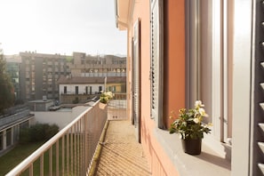 Enjoy the urban view from this balcony with a metal railing and potted plants.