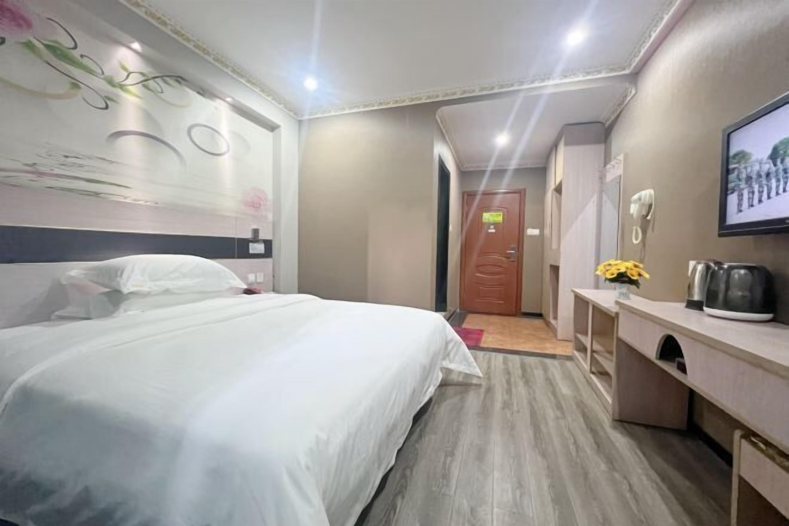 Une chambre d’hôtel comprenant un lit, un bureau avec une bouilloire, une télévision et une porte donnant sur une autre pièce.