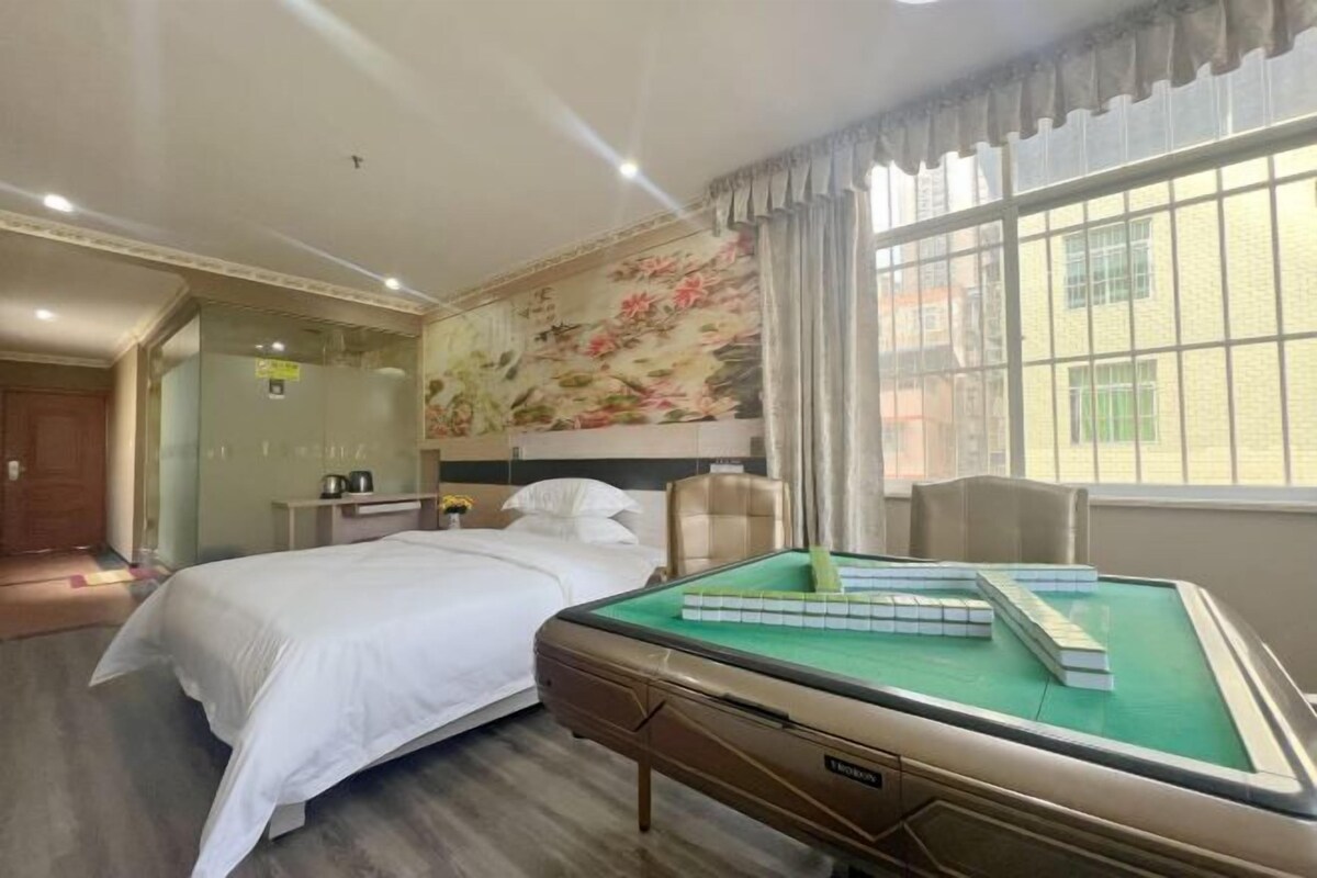 A hotel room with a bed, a green pool table, a decorative wall, and a window with curtains.