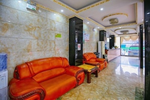 A hotel lobby with two red leather sofas, a reception desk, and a marble floor. - Gezi Hotel (Keyuan Avenue Branch) (Nanning)