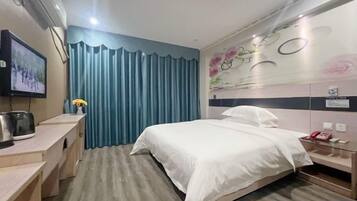 A hotel room with a bed, a desk, a TV, and a curtain.