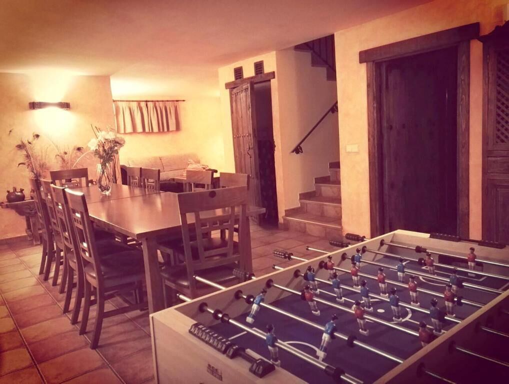 Un comedor con mesa de futbolín, sillas y una lámpara de mesa.