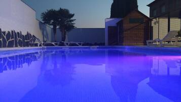 Een seizoensgebonden buitenzwembad, ligstoelen bij het zwembad