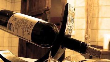 Una botella de vino sobre una encimera de cocina, junto con una copa y un sacacorchos.