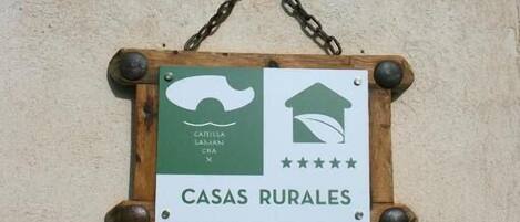 Un letrero que dice 'CASAS RURALES' con un diseño rústico, que incluye un icono de una casa y una valoración en estrellas.