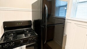 Una cocina con estufa negra, refrigerador negro y armarios blancos.