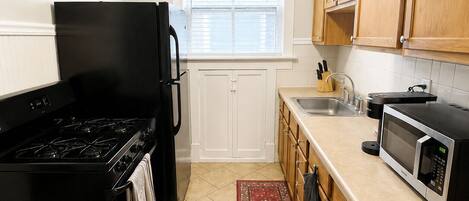 Una cocina con estufa, refrigerador, microondas y armarios de madera.