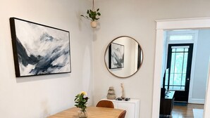 Un comedor con una mesa de madera, sillas marrones, un mueble blanco y un espejo en la pared.