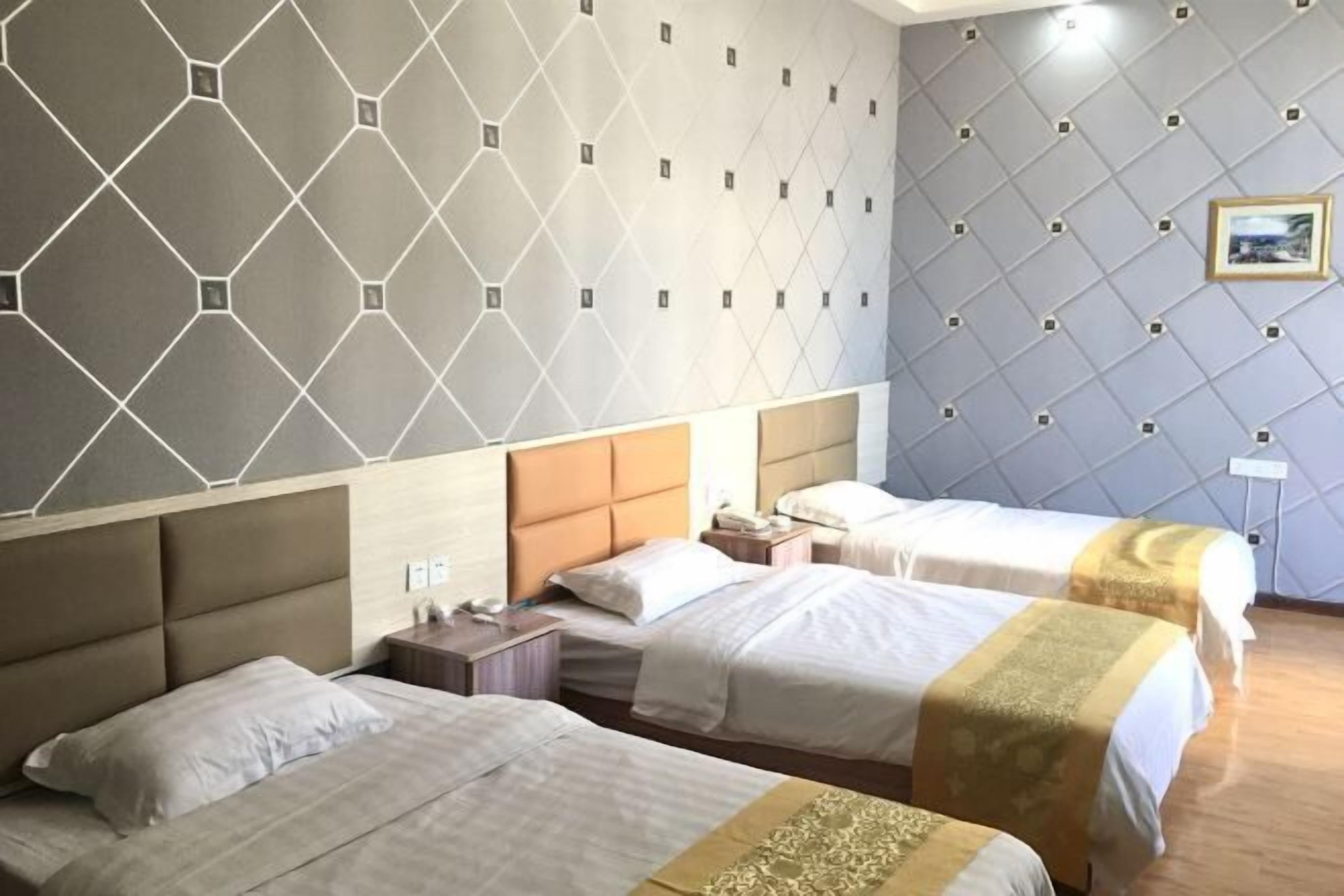 A hotel room with three beds, a wooden headboard, a wall with a geometric pattern, and a framed picture on the wall.
