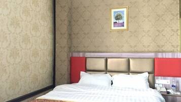 Een hotelkamer met een bed, een hoofdeinde, een nachtkastje en een lijst met een foto aan de muur.