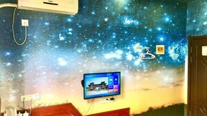 A room with a starry night ceiling mural, a mounted television, and a wooden bench. - Yilu Tongxing Chain Hotel (Suixi)
