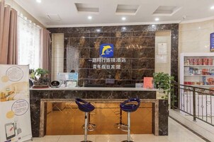 Zona de recepción de un hotel con mostrador de mármol, un logotipo y dos taburetes de bar.
