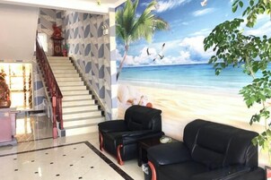 Un vestíbulo con un mural de playa, una escalera y asientos de cuero negro.