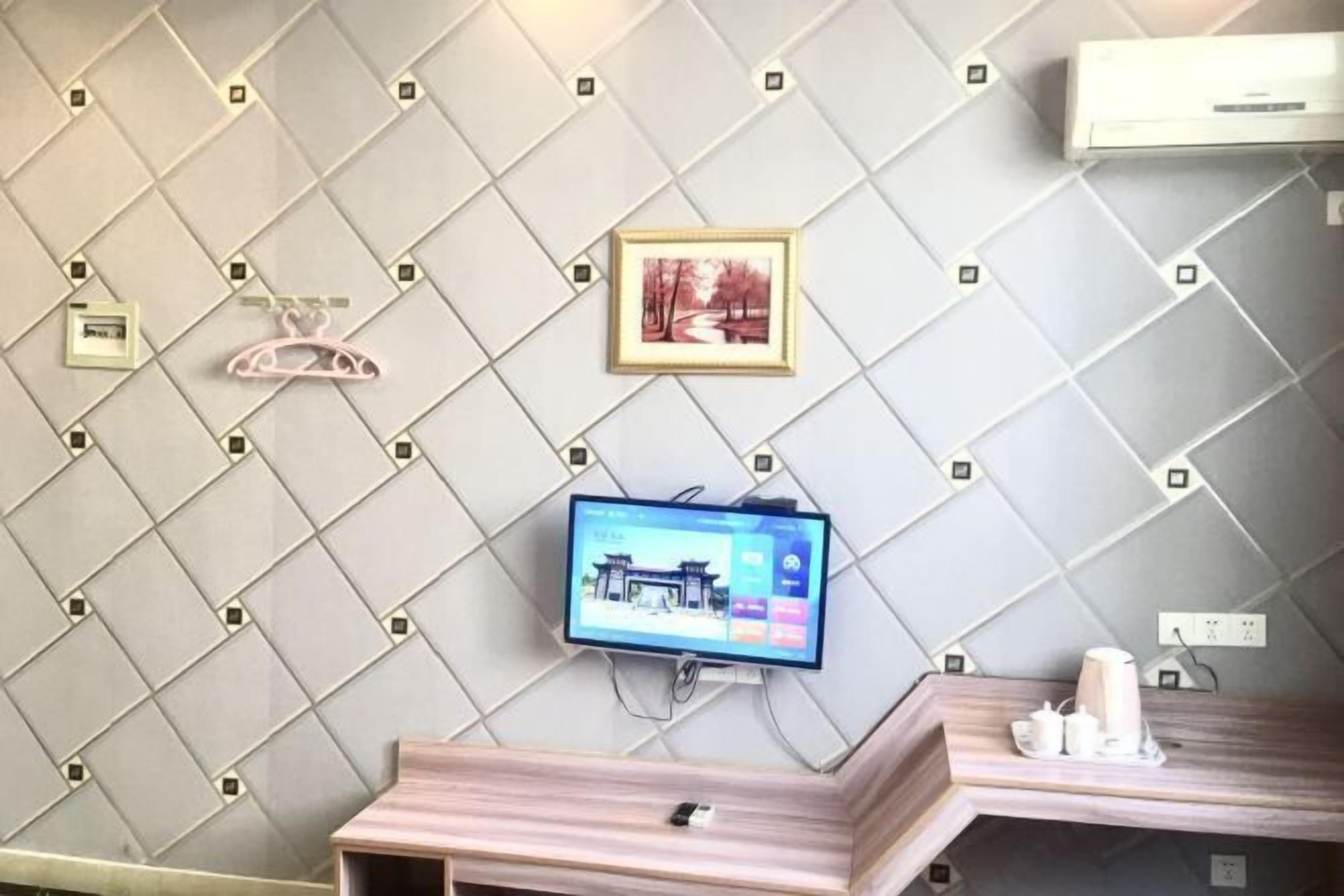Un baño moderno con pared de azulejos, televisor montado y tocador de madera con espejo.