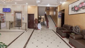 A hotel lobby with a marble floor, a staircase, leather sofas, and a digital display board. - Yilu Tongxing Chain Hotel (Suixi)
