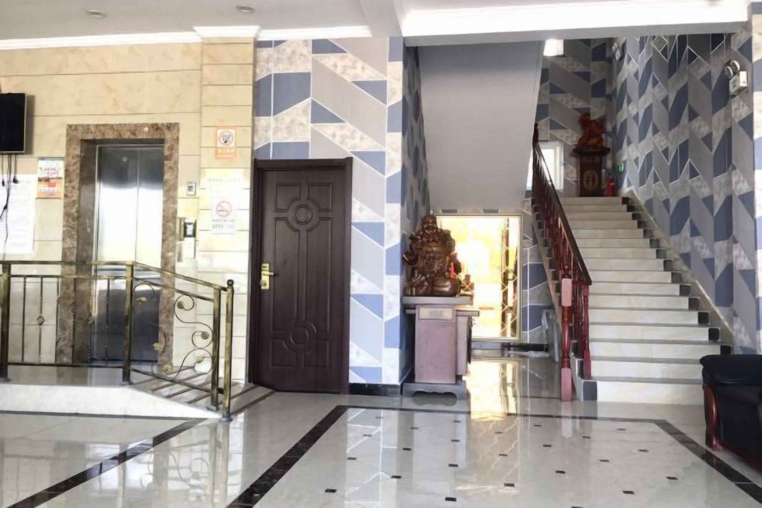 Un vestíbulo con suelo de mármol, una escalera y una puerta con un diseño geométrico en la pared.