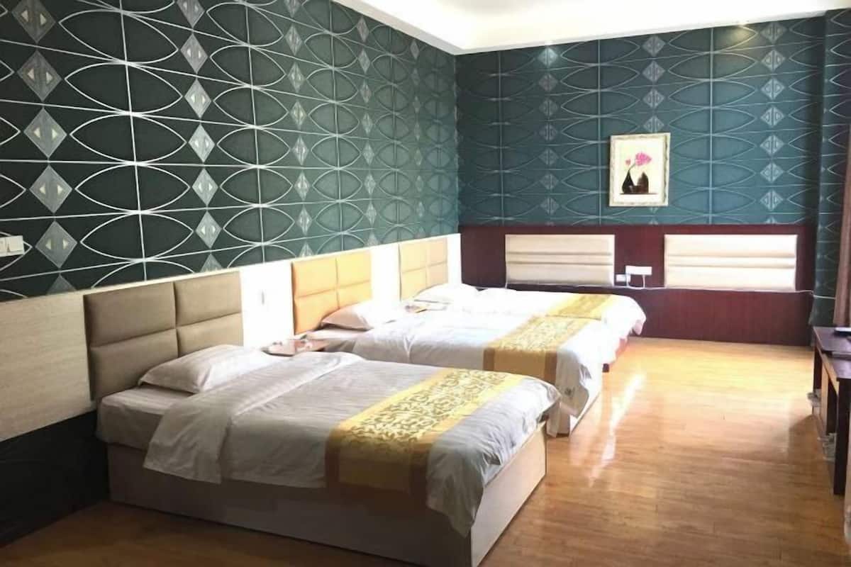 Habitación de hotel con dos camas, suelo de madera y pared estampada.