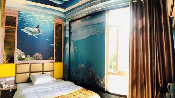 A room with a bed, a nightstand, and a window with curtains. - Yilu Tongxing Chain Hotel (Suixi)