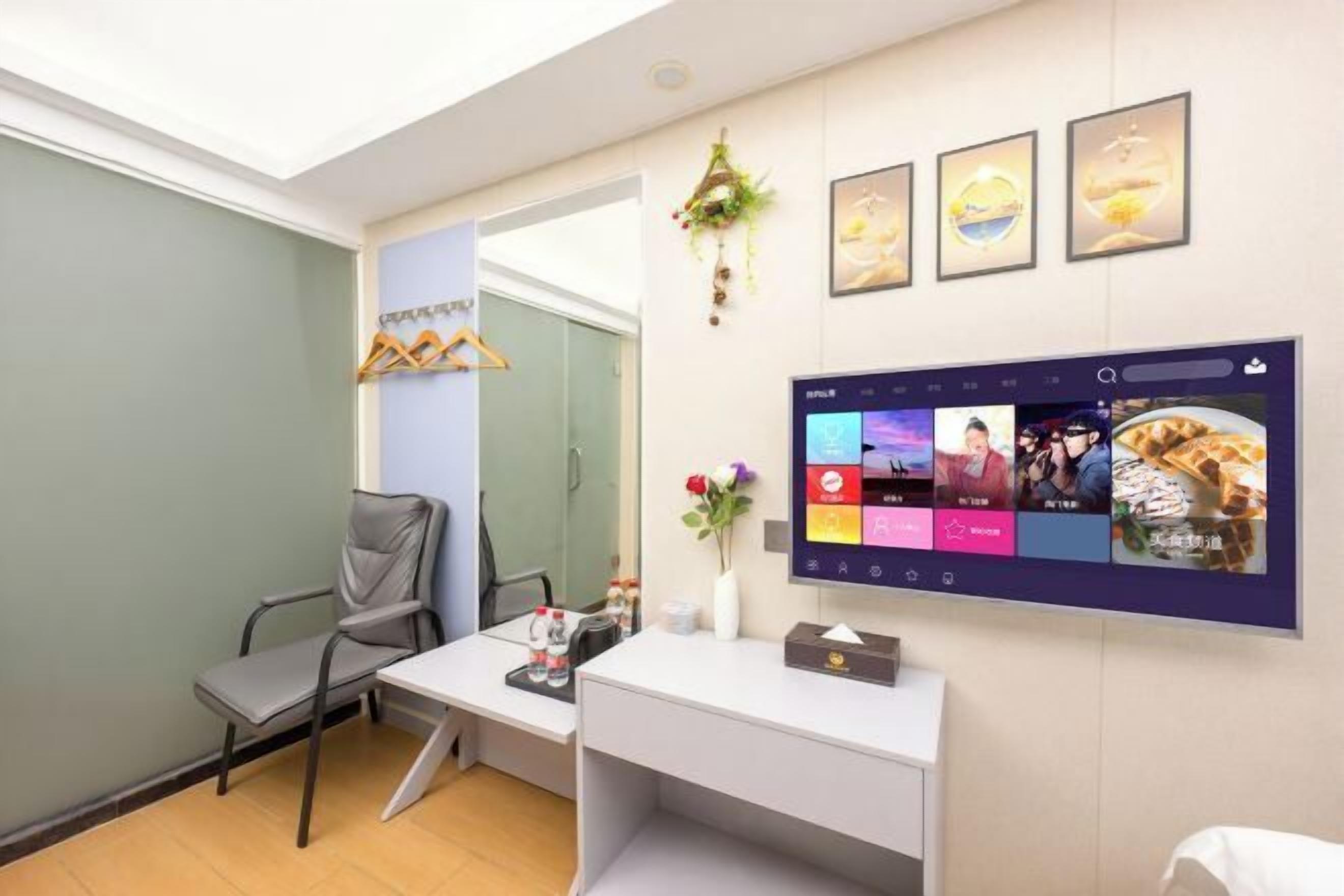 A reception area with a desk, chair, wall-mounted TV, and framed pictures.