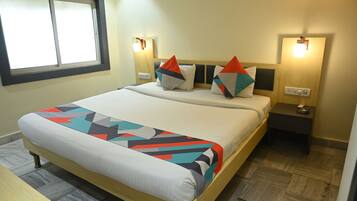 A neatly made bed with a geometric-patterned bedspread, two bedside lamps, and a small bedside table with a lamp.